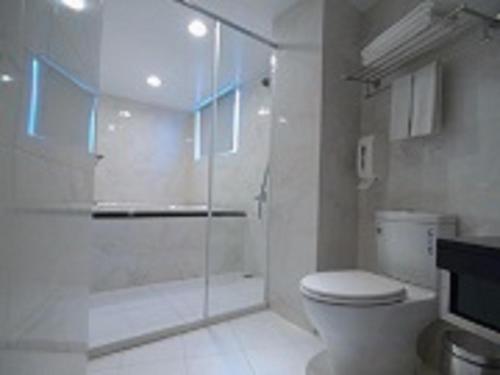 a white bathroom with a shower and a toilet at Grace Hotel in Taipei
