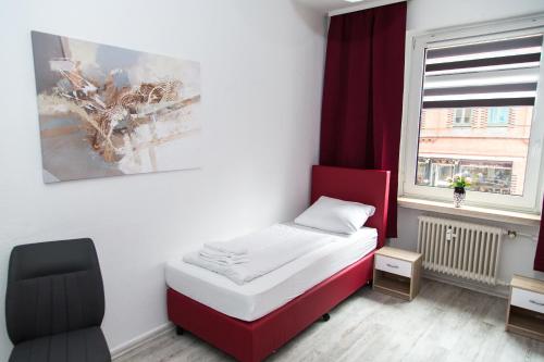 ein kleines Schlafzimmer mit einem roten Bett und einem Stuhl in der Unterkunft Othman Appartements Falkenstraße 26 3OG L in Hannover