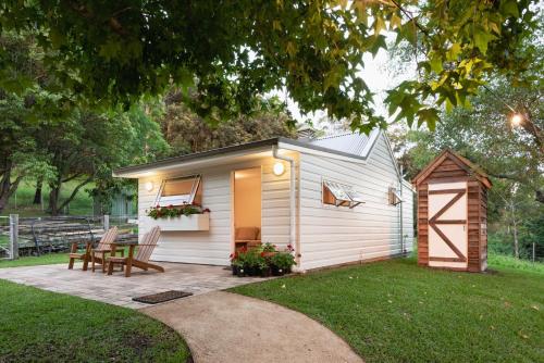 a small white shed with a table and chairs in a yard at Yarrawong Farm, near Berry in Jaspers Brush