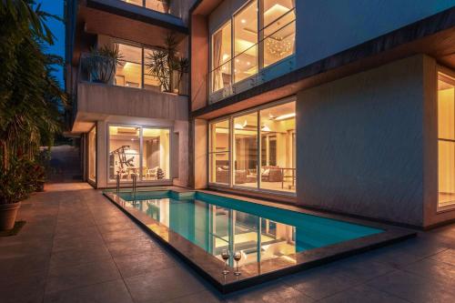 an external view of a house with a swimming pool at StayVista's Bianco Villa - Hill-View Villa with Private Pool, Jacuzzi, Gym & Games Room in Lonavala