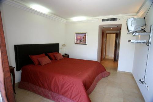 a bedroom with a red bed and a tv at Hotel Soltroia - Foz Do Sado in Troia