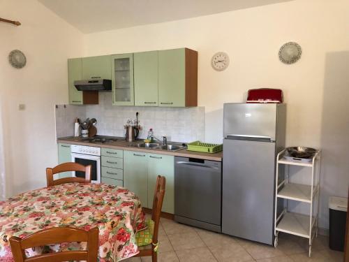 a kitchen with a table and a stainless steel refrigerator at Apartments Vodarić Loznati in Cres