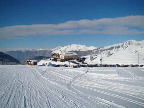 a ski lodge on a snowy mountain with tracks in the snow at Albergo Venezia in Passo Rolle