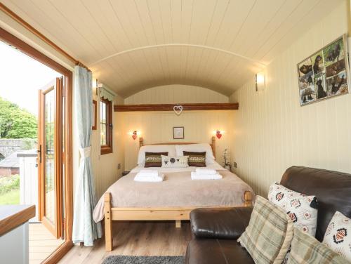 een slaapkamer met een bed en een bank bij Llety'r Bugail 2 in Caernarfon