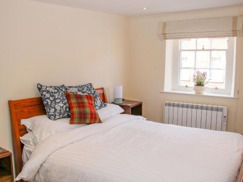 a bedroom with a white bed and a window at 138C Old Star & Garter Mews in Ludlow