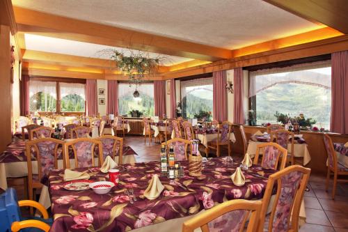 a dining room with tables and chairs and windows at Albergo Venezia in Passo Rolle