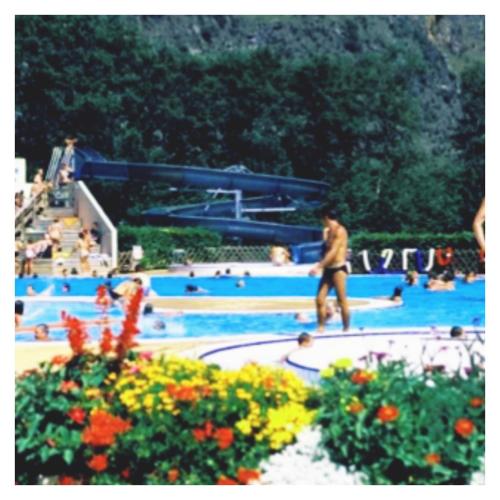 a man walking in a swimming pool with people in it at L'émeraude in Le Bourg-dʼOisans