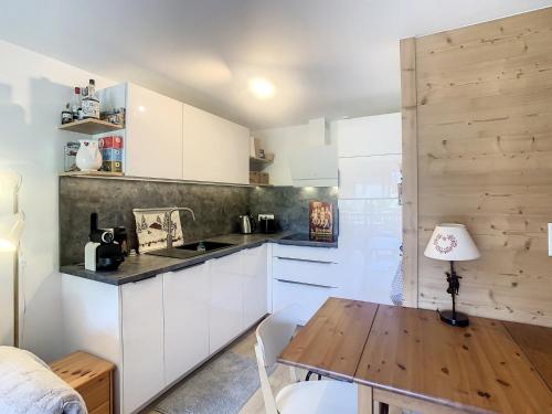 une cuisine avec des armoires blanches et une table en bois dans l'établissement Appartement 2 pièces + cabine à proximité du village et téléski, cuisine équipée - FR-1-560-89, à Combloux