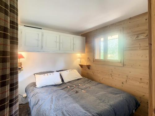 un lit dans une chambre avec un mur en bois dans l'établissement Appartement 2 pièces + cabine à proximité du village et téléski, cuisine équipée - FR-1-560-89, à Combloux