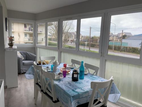 une salle à manger avec une table, des chaises et des fenêtres dans l'établissement Charmant T2 à Cabourg, proche centre et plage, calme, loggia, ascenseur, animaux acceptés - FR-1-487-337, à Cabourg