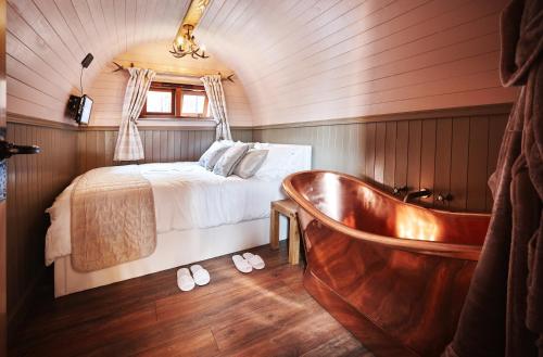 a bedroom with a bed and a bath tub at Luxury Mary's Croft with Swedish Hot tub and BBQ HUT in Shrewsbury