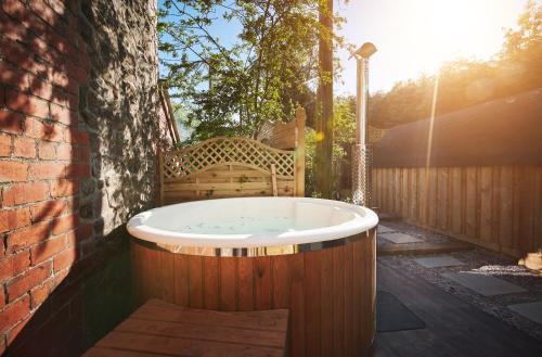 a bath tub sitting on a patio with a bench at Luxury Mary's Croft with Swedish Hot tub and BBQ HUT in Shrewsbury