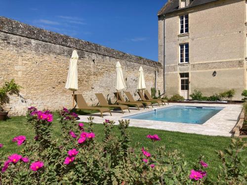 a pool with chairs and umbrellas next to a building at Le Domaine de l'Hostellerie in Le Fresne-Camilly