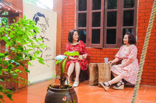 two women sitting on a bench next to a plant at Trang An Village Homestay in Ninh Binh