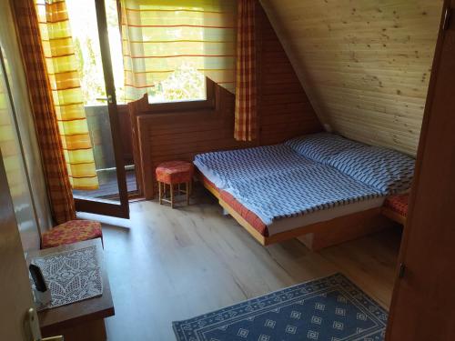 una piccola camera con un letto e due sedie e una finestra di Pelso Vendégház a Balatonmáriafürdő