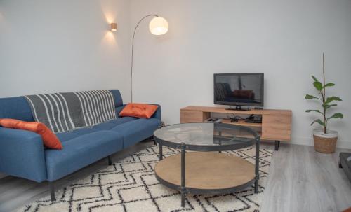 sala de estar con sofá azul y mesa de cristal en Le petit cocon de la butte, en Gourdon-en-quercy