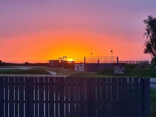 a sunset over a parking lot with a fence at Mawgan Pads Perranporth in Cubert