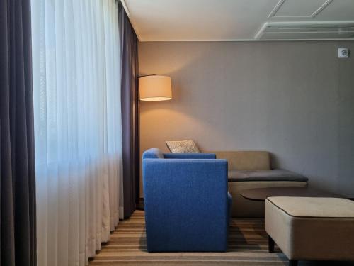 a living room with a blue chair and a couch at Avonhotel Gunsan in Gunsan