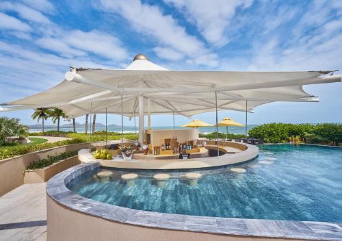 a pool at a resort with a large white umbrella at Holiday Inn Resort Ho Tram Beach by IHG in Ho Tram