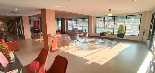 an empty lobby with chairs and tables and windows at Sriracha Orchid Hotel in Si Racha