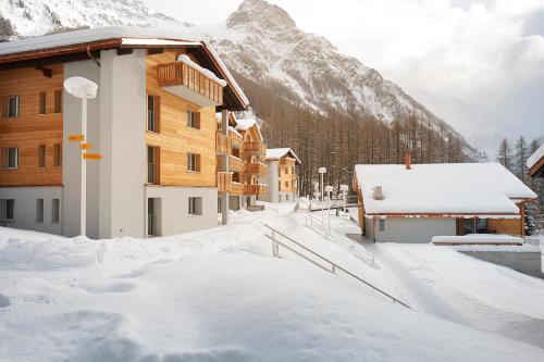 a building covered in snow with a mountain in the background at Reka-Feriendorf Zinal in Zinal
