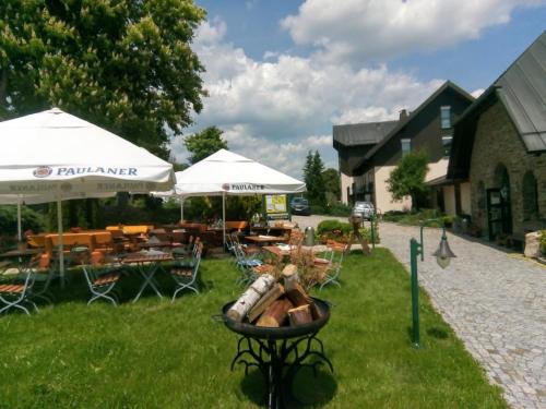 a yard with tables and chairs and umbrellas at Landhotel Rittersgrün in Breitenbrunn