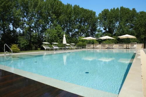 a large swimming pool with chairs and umbrellas at Agriturismo Villa Almè in Oderzo