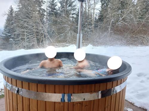 two people in a hot tub in the snow at LE CHALET VOSGIEN bain nordique Kota Grill in Gérardmer