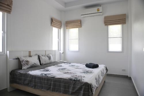 a bedroom with a bed with white walls and windows at KK Garden 小院 in Hua Hin