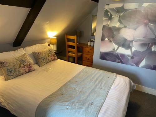 a bedroom with a white bed with a painting on the wall at The Mansion House Hotel in Holbeach
