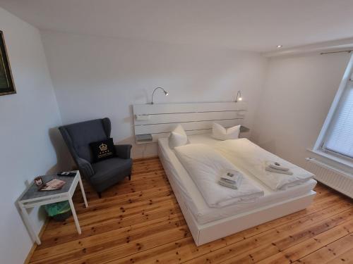 a white bedroom with a bed and a chair at Hotel & Restaurant "Deutscher Kaiser" in Perleberg
