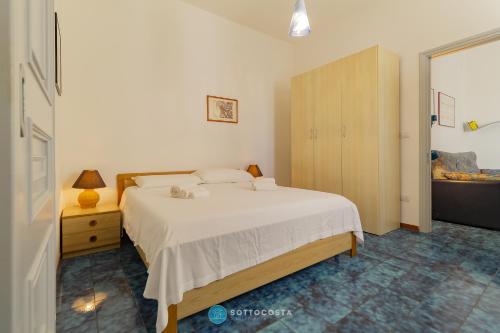 a bedroom with a white bed and a wooden cabinet at BLUE HOUSE - SAN FOCA in San Foca