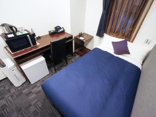 a room with a bed and a desk with a computer at HOTEL LiVEMAX Nagoya Sakae East in Nagoya