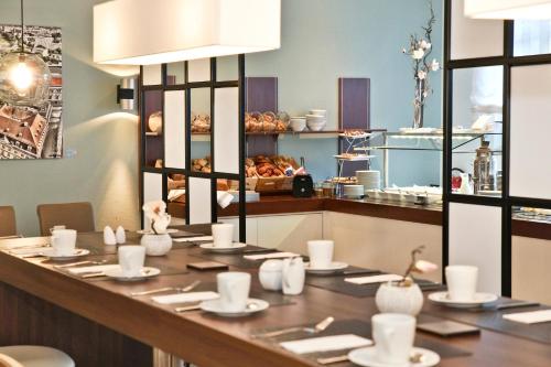 a restaurant with a long table with plates and cups at Best Western Macrander Hotel Dresden in Dresden
