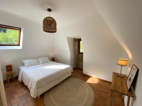 a bedroom with a white bed and a rug at Les Courtines - Appartement de caractère à la Roque-Gageac - Les Cerisiers in La Roque-Gageac