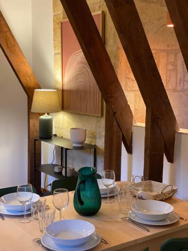 a wooden table with plates and wine glasses on it at Les Courtines - Appartement de caractère à la Roque-Gageac - Les Cerisiers in La Roque-Gageac