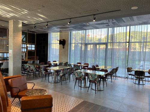 a dining room with tables and chairs and windows at Occidental Tanger in Tangier