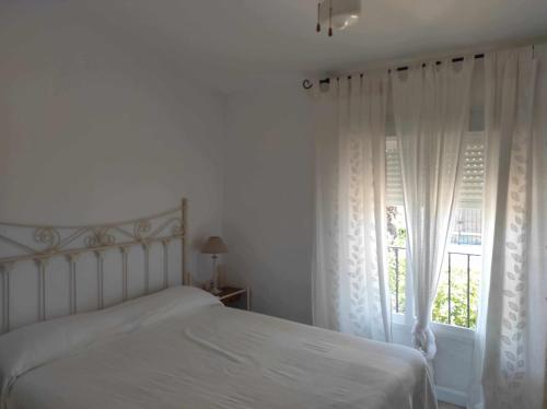 a bedroom with a white bed and a window at Casa La Gaviota en el centro de Zahara in Zahara de los Atunes
