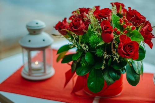 a red vase filled with red roses and a candle at HT Houseboats - domki na wodzie - sauna, motorówka, rowerki wodne in Mielno