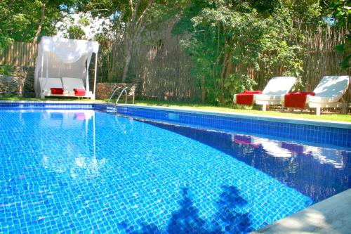 a swimming pool with two lawn chairs at Terra Dos Goitis - Chalés - Pipa in Pipa