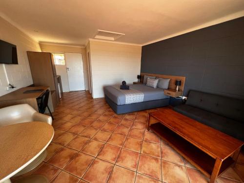 a bedroom with a bed and a couch in a room at Hospitality Port Hedland in Port Hedland