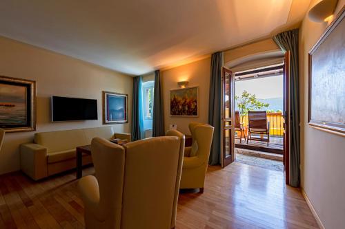 a living room with chairs and a table and a television at Hotel Baia D'Oro - Adults Only in Gargnano