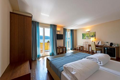 a hotel room with a bed and a table and a desk at Hotel Baia D'Oro - Adults Only in Gargnano