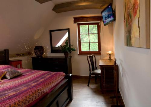 a bedroom with a bed and a desk and a window at Penzion Rozmarýn in Vsetín