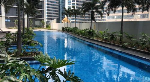 a large blue swimming pool with palm trees and buildings at Josh's Place at One Eastwood Avenue Tower 1 in Manila