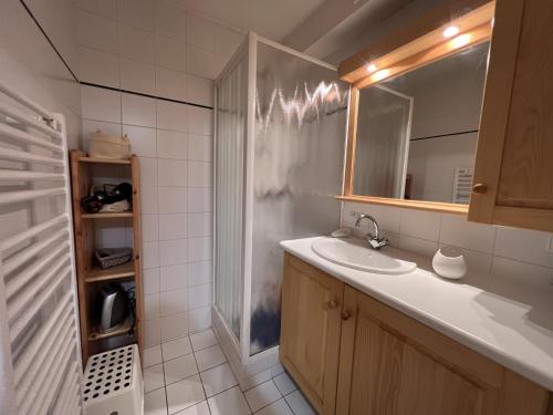 une salle de bain avec un lavabo et une douche avec un miroir dans l'établissement Tendieu Soleil B - Appartement dans chalet, vue montagnes, à La Clusaz