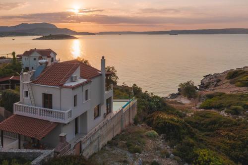a house on a hill next to a body of water at Villa Almy in Plaka