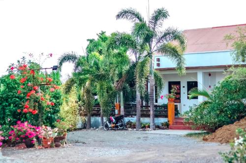 a house with palm trees and a motorcycle in front of it at Airport View Hotel in Vigan