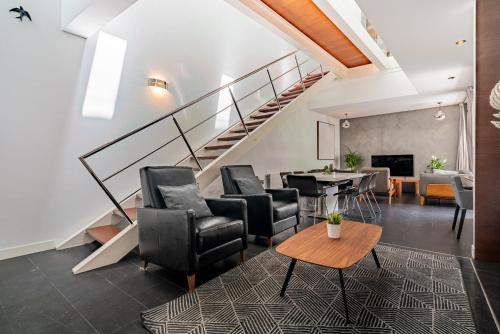 a living room with chairs and a table and stairs at VLVilla - Villa de lujo en Valencia con piscina privada y sala de cine in Burjasot