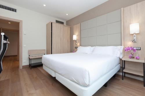 a bedroom with a large white bed and a desk at Hotel Puerta de Bilbao in Barakaldo